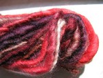 Red, brown, and white spun yarn close up thumbnail.