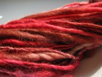 Red, brown, and white spun yarn close up thumbnail.