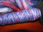 Red, pink, and blue glitter spun yarn on drop spindle thumbnail.