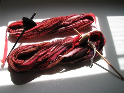 Red, brown, and white spun yarn with two drop spindles.